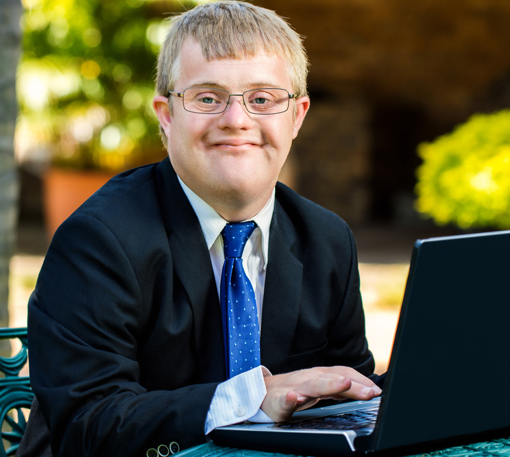 Young person wearing a suit outdoors with a laptop